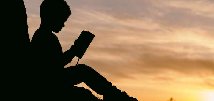 Niño leyendo al atardecer.