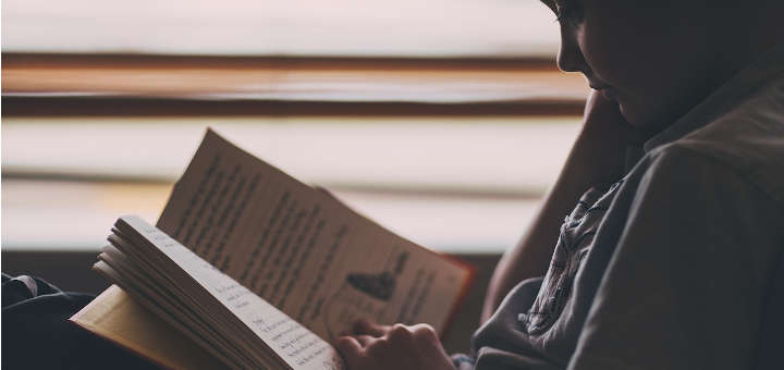 Niño leyendo en una habitación con luz tenue.